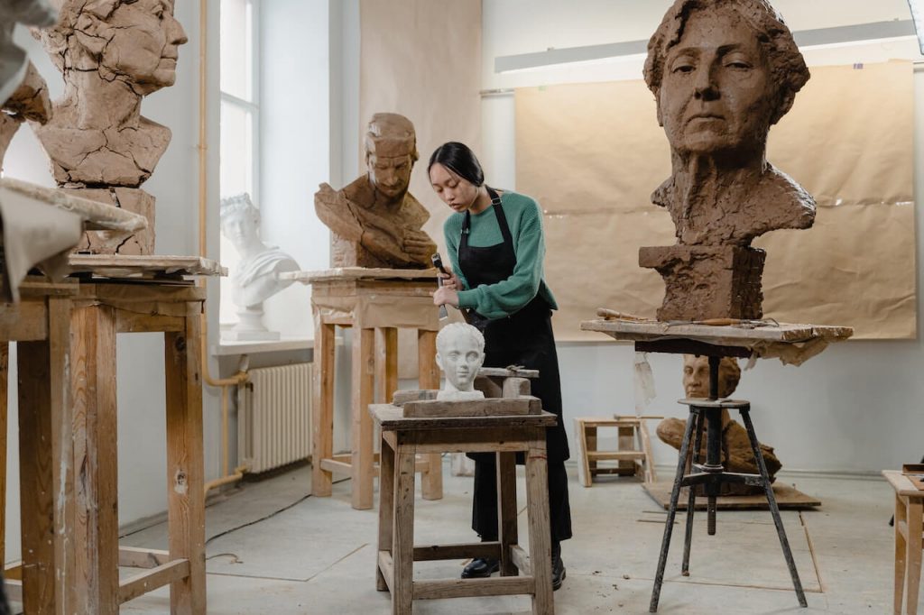 Una escultora inmersa en su proceso creativo, rodeada de herramientas y materiales en su puesto de trabajo